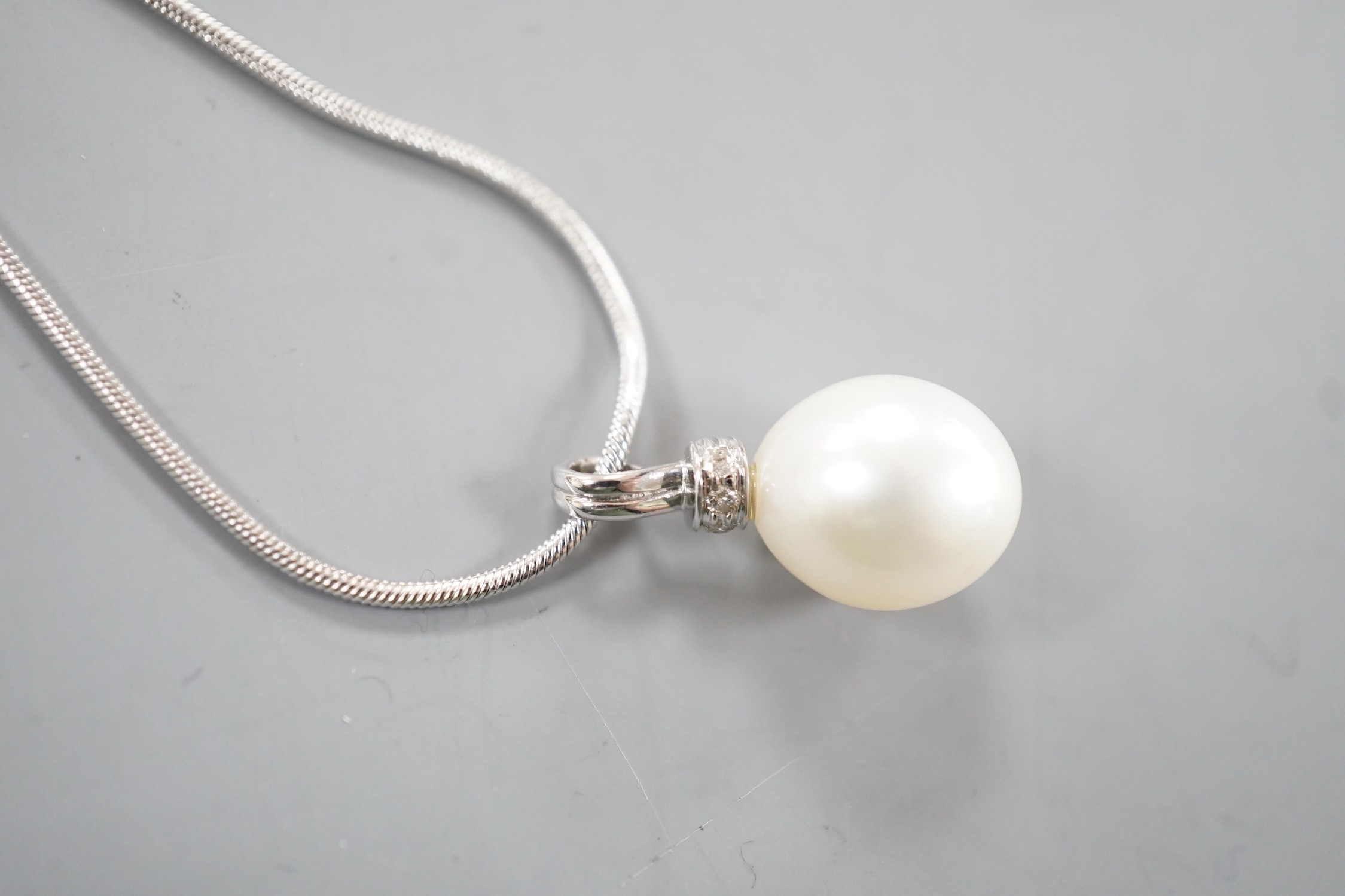 A modern 18ct white, gold, cultured pearl and diamond set pendant, 20mm, gross 2.7 grams, on a modern 9ct white gold chain, 44cm, 4.2 grams.